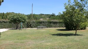 Un espace extérieur verdoyant avec une balançoire, une table de pique-nique et un arbre.