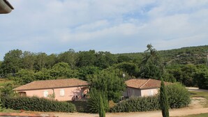Une propriété rurale comprenant deux bâtiments, entourée d’une végétation luxuriante et de collines.