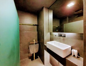 Ein modernes Badezimmer mit einem großen Waschbecken, einem Handtuchhalter und einem Spiegel.