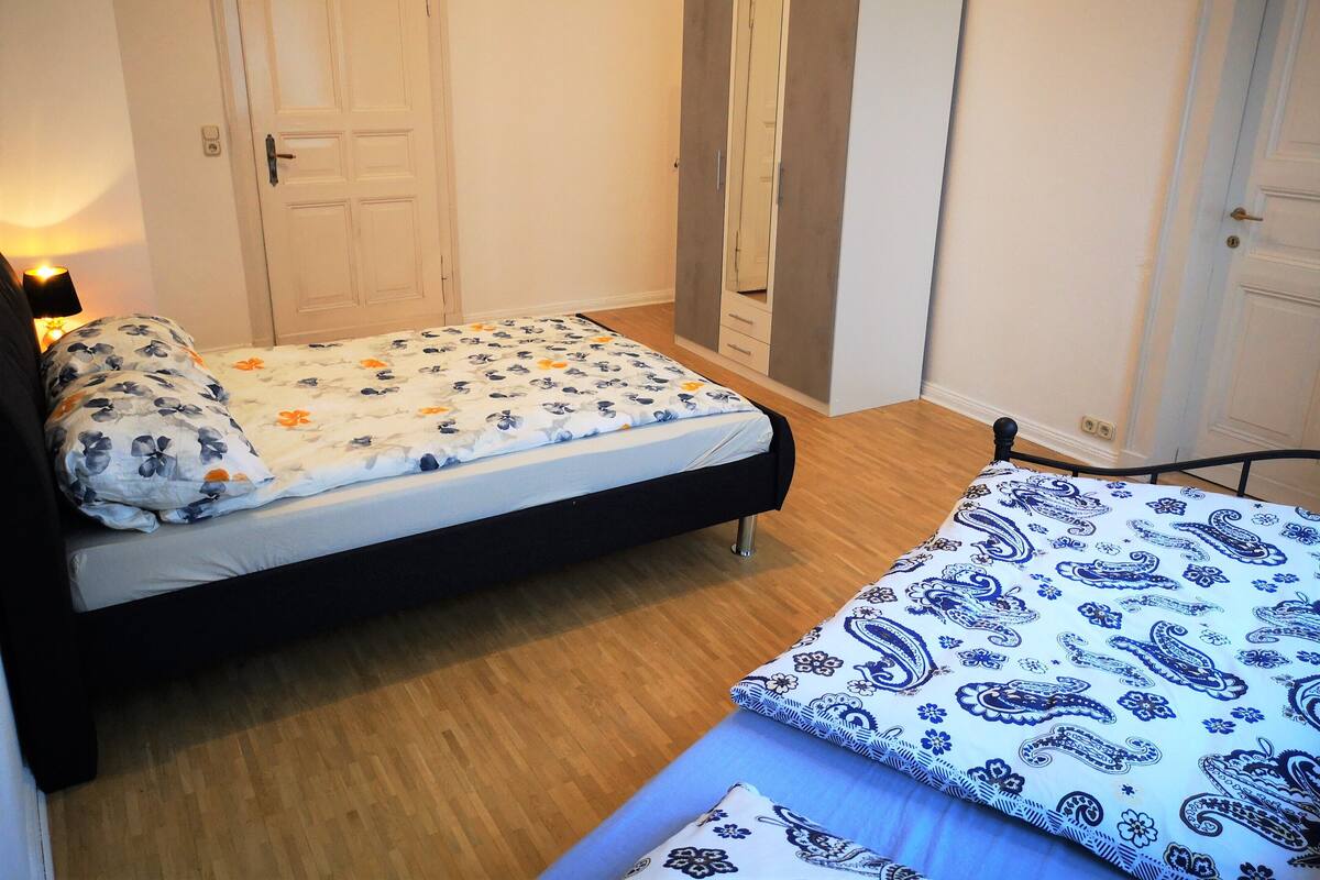 A bedroom with a bed, a wardrobe, and a bedside table.