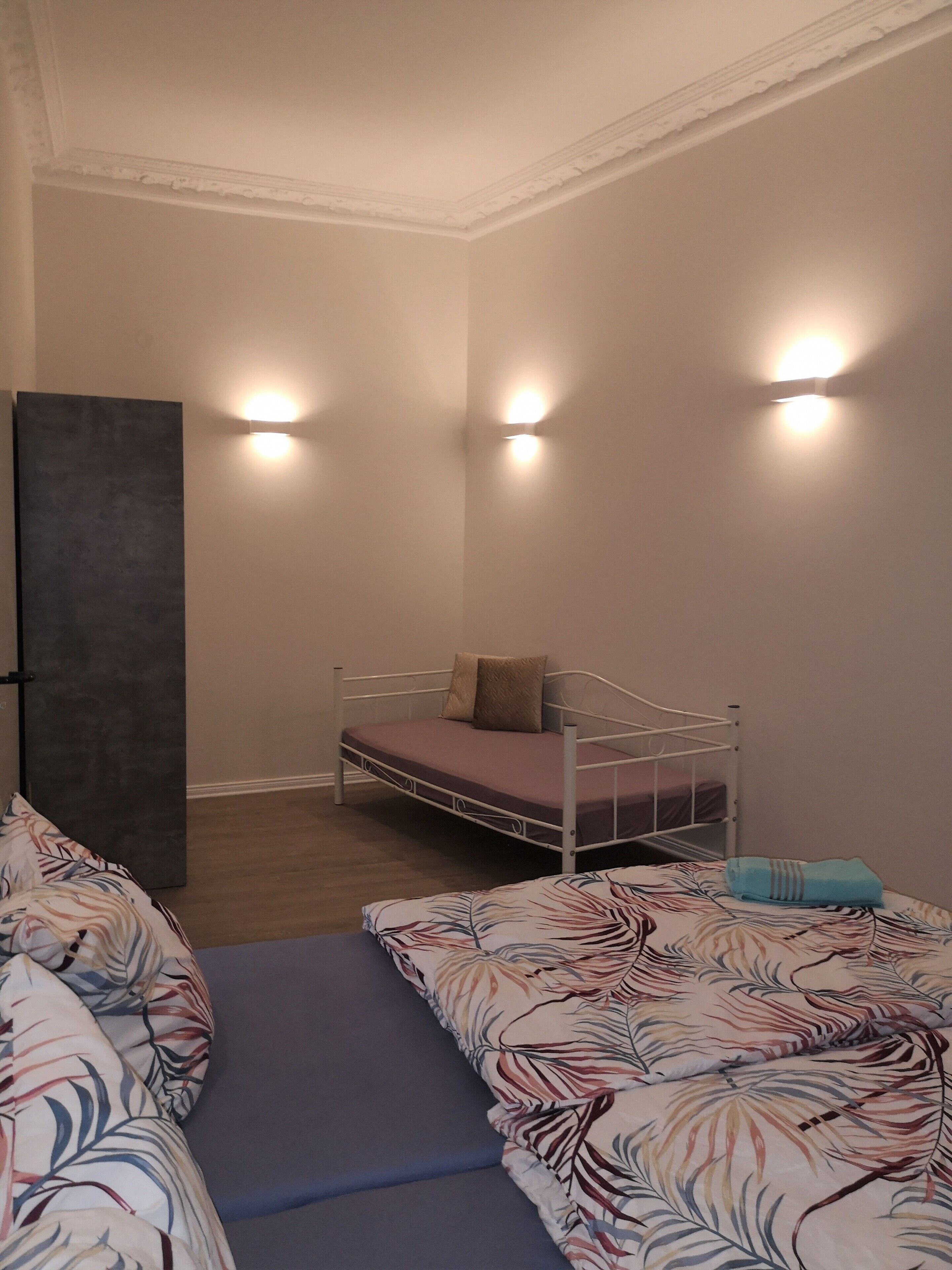 A bedroom with a bed, a wardrobe, and two wall-mounted lights.
