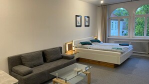 Un dormitorio moderno con una cama, un sofá y una mesa de centro de vidrio.