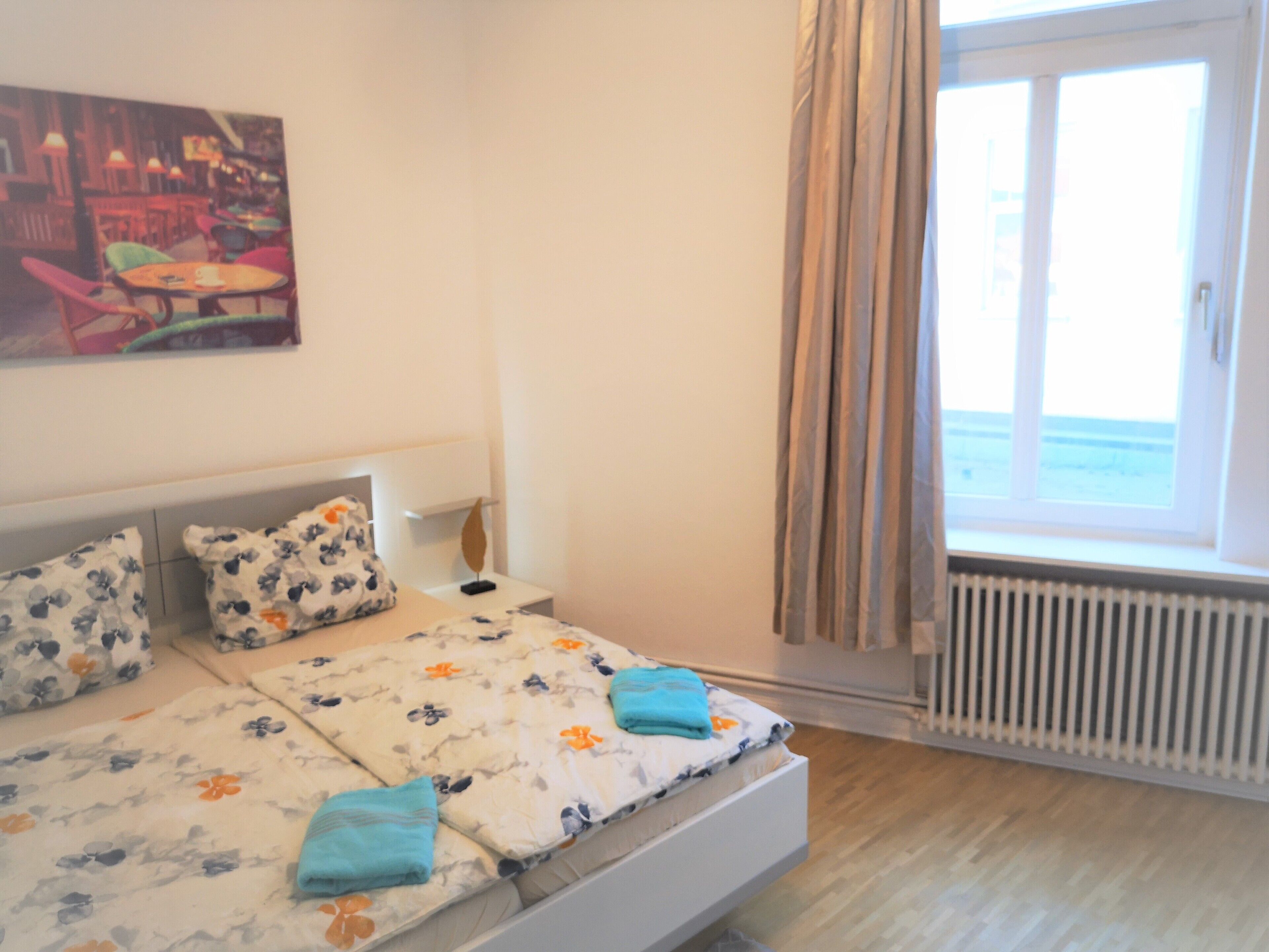 Une chambre à coucher avec un lit, des oreillers, une table de chevet et une fenêtre avec des rideaux.