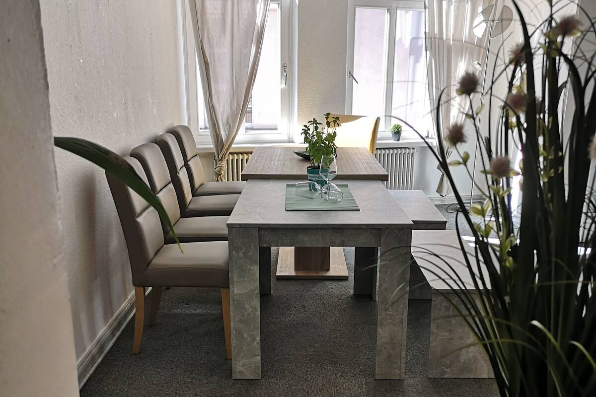 A modern living room with a sofa, a dining table, and a potted plant.