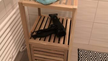 A small wooden shelf with a folded blue towel and a black hairdryer.