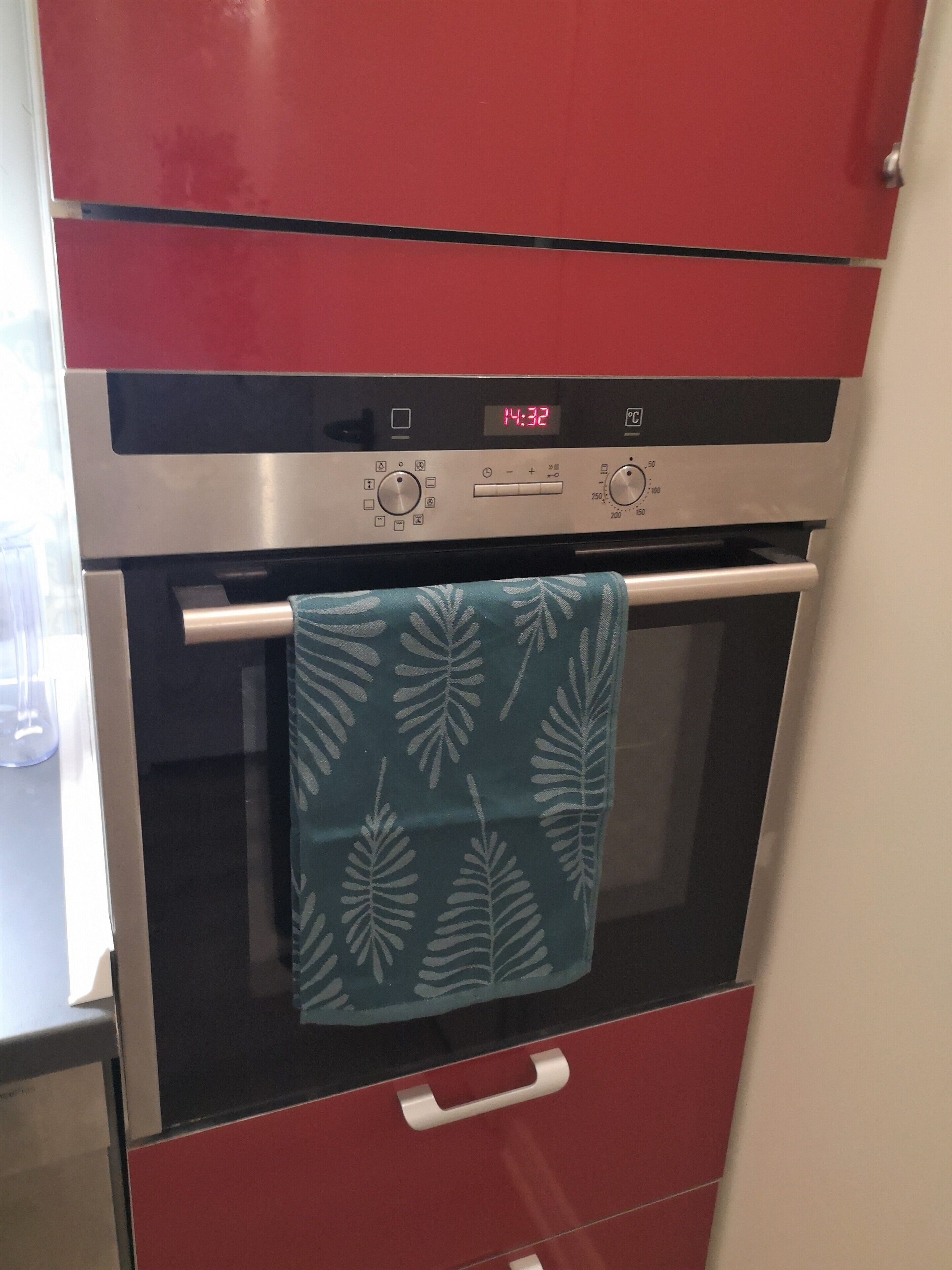 A kitchen with a red oven and a stainless steel range hood.