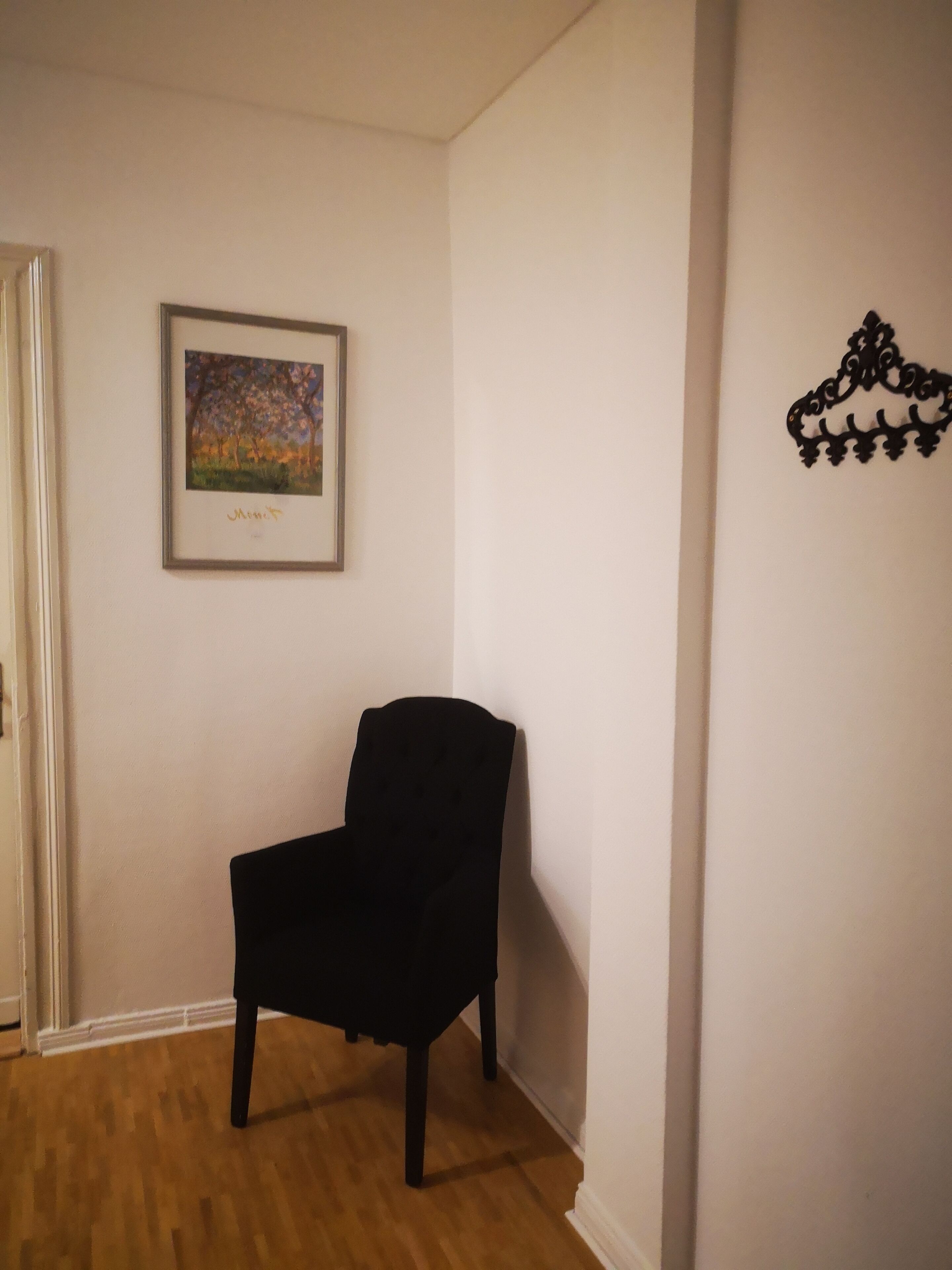 Una habitación con una silla negra, un cuadro enmarcado en la pared y un adorno mural.