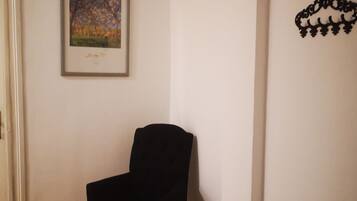 Una habitación con una silla negra, un cuadro enmarcado en la pared y un adorno mural.