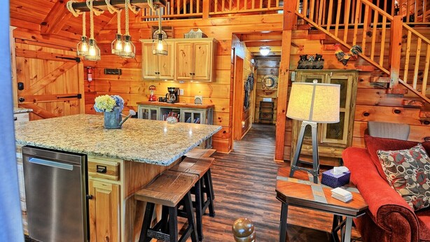 Interno di una baita in legno con cucina, sala da pranzo e una scala.