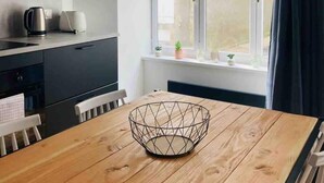 Una cocina moderna con armarios oscuros, una mesa de comedor de madera y una ventana con cortinas.
