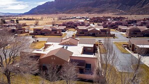 A residential area with houses featuring red-tiled roofs and a mountainous backdrop. - T4 Corner Moab Retreat with Private Garage in Rim Village (Moab)