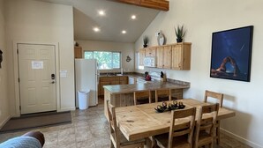 A kitchen with wooden cabinets, a dining table, and chairs. There is a refrigerator, a microwave, and a sink. - T4 Corner Moab Retreat with Private Garage in Rim Village (Moab)