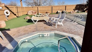 A backyard with a hot tub, patio furniture, and a wooden fence. - T4 Corner Moab Retreat with Private Garage in Rim Village (Moab)