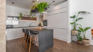 A modern kitchen with a central island, bar stools, hanging plants, and built-in appliances. - Villa Le' Tini Luxury - Luxury Residence (Podstrana)