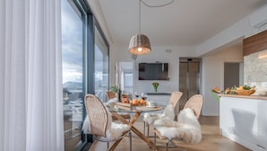 A modern kitchen with a large window, a dining area with wicker chairs, and a view of mountains. - Villa Le' Tini Luxury - Luxury Residence (Podstrana)
