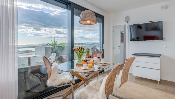 A modern dining area with a glass table, wicker chairs, and a view of the cityscape through large windows. - Villa Le' Tini Luxury - Luxury Residence (Podstrana)