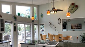 Una cucina moderna con piano cottura integrato, mobili bianchi e un'area pranzo con sedie in legno.