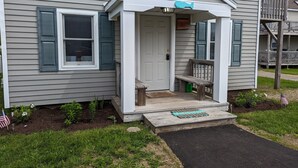 Une maison avec un porche à l’avant, une porte et un petit banc.