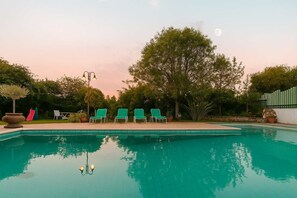 A swimming pool with lounge chairs and a tree in the background.