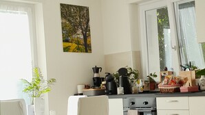 A modern kitchen with white cabinets, a dining area with a table and chairs, and a large window providing natural light. - Hidden Gem in Trentino  Authentic Alpine Stay in the Dolomites with AC (Mattarello)