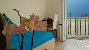 A bedroom with a bed, a desk, and a balcony with a view of the mountains. - Hidden Gem in Trentino  Authentic Alpine Stay in the Dolomites with AC (Mattarello)