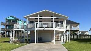 Ein zweistöckiges Haus mit Balkon, Garage und einer kleinen Veranda.