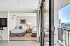 A hotel room with two beds, a TV, a painting, and a balcony with a city view. - Waikiki Banyan Condo With Panoramic 37th Floor Ocean Views (Honolulu)