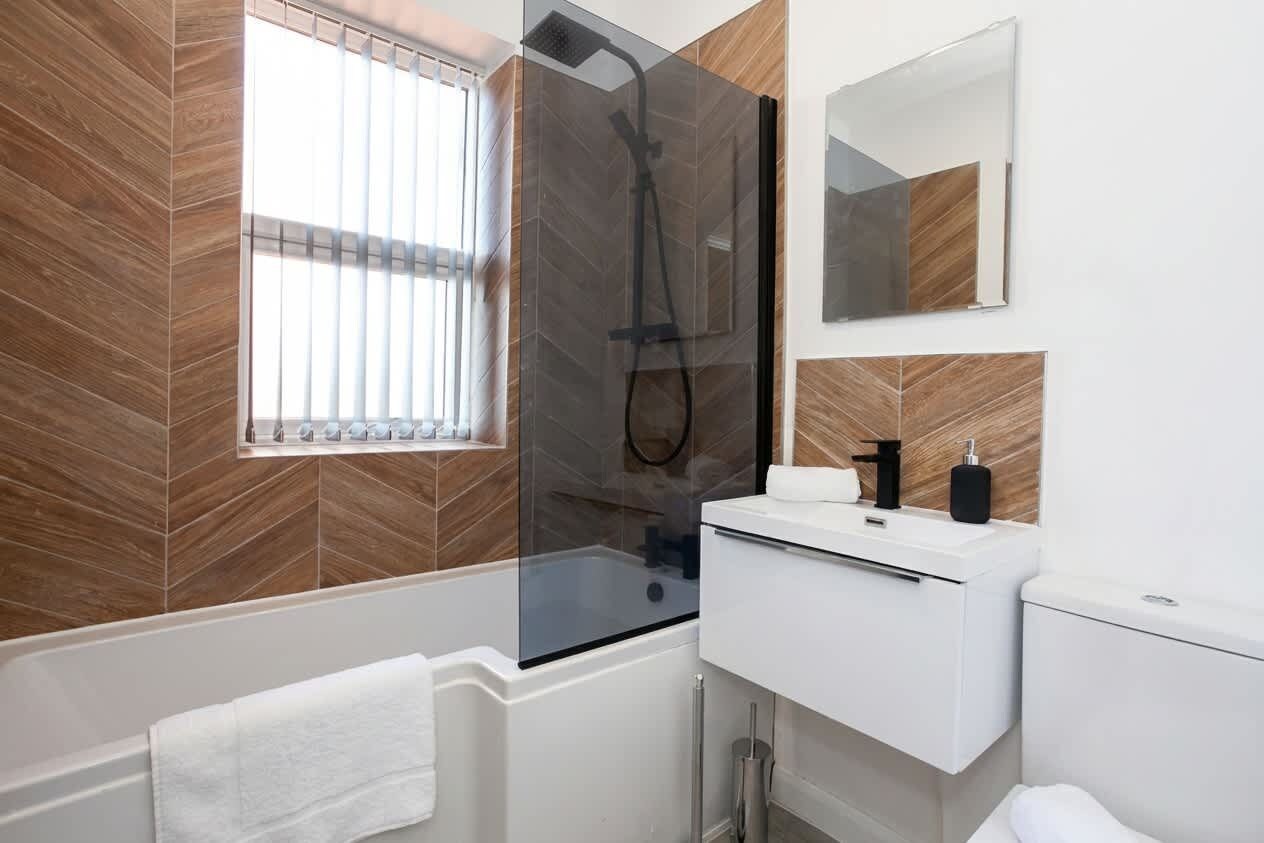 A modern bathroom with a glass-enclosed shower, a white sink, and a mirror.