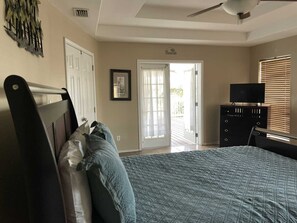 A bedroom with a bed, a dresser, a television, and a door leading to a balcony. - 126 E Pike 4 Bedroom Home by RedAwning (South Padre Island)