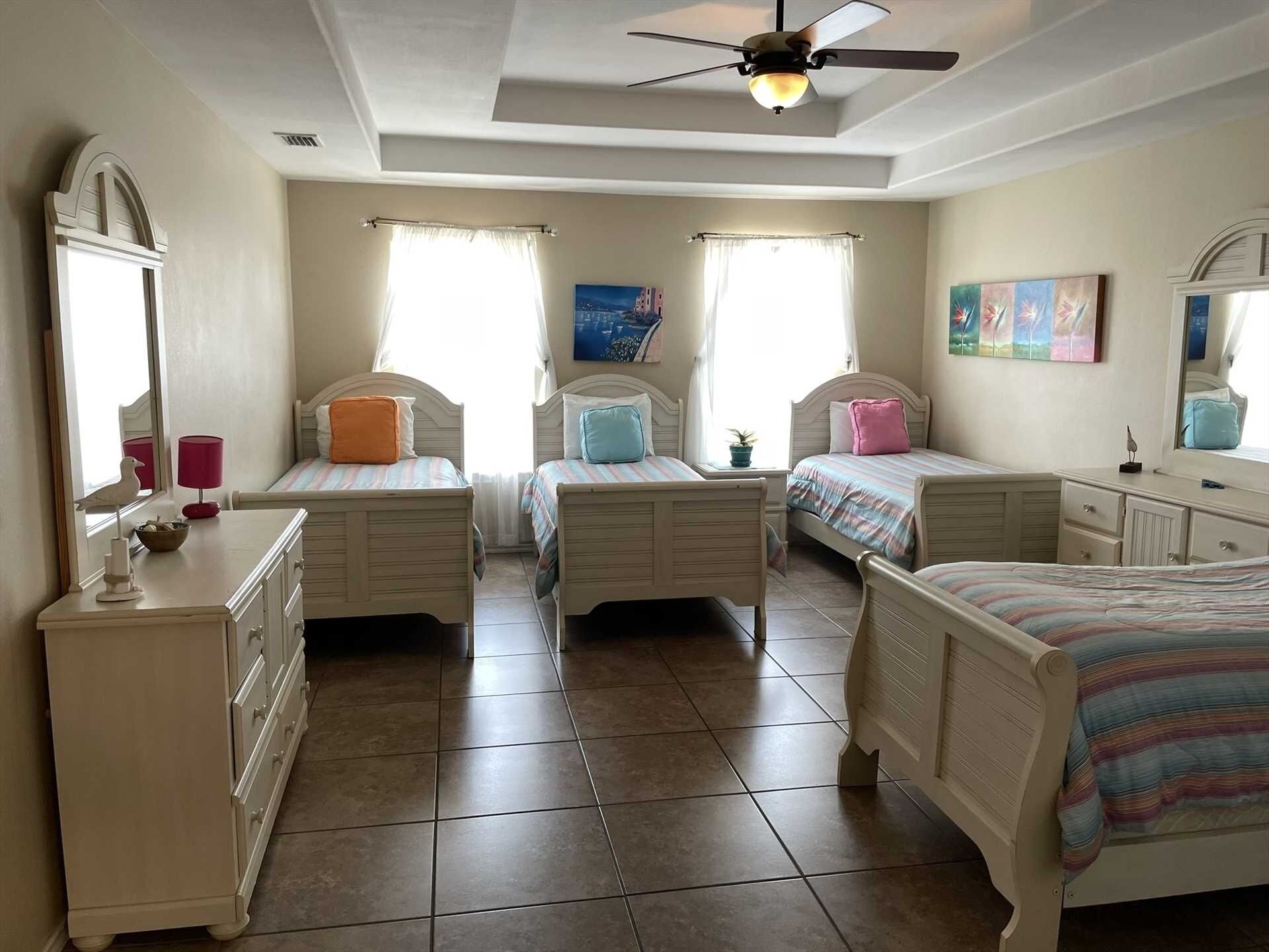 A bedroom with three beds, a ceiling fan, and a dresser.