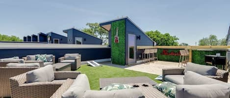 A rooftop patio with outdoor furniture, a green wall with a guitar, and a sign that reads "Mansfield."