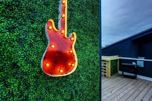 A guitar-shaped light fixture against a green wall, a wooden deck, and a dark blue building. - music city themed home with garage game room, sleeps 12 in east nashville (Nashville)