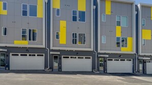 Een modern meerlaags gebouw met een gevel in grijs en geel, met meerdere garagepoorten op de begane grond.