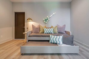 Ein modernes Wohnzimmer mit einer Couch, gemusterten Kissen, einer Gitarren-Wanddekoration, einer Lampe und einer Tür.