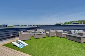 Eine Dachterrasse mit Gartenmöbeln und Kunstrasen.