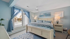 A bedroom with a bed, a ceiling fan, a window with curtains, a nightstand, and a lamp. - Located on prime street in Dewey Beach walking to everything with brand new POOL (Dewey Beach)