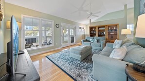 A living room with a sofa, ottoman, and a TV on a stand. - Located on prime street in Dewey Beach walking to everything with brand new POOL (Dewey Beach)