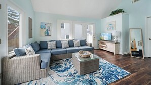 A living room with a sectional sofa, wicker chairs, a glass coffee table, and a blue patterned rug. - Located on prime street in Dewey Beach walking to everything with brand new POOL (Dewey Beach)