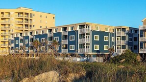 Una serie di edifici a più piani con balconi, probabilmente appartamenti residenziali, accanto a una spiaggia sabbiosa con scarsa vegetazione.