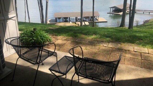 A patio with two metal chairs and a small table, overlooking a lake with a dock and a building. - What A View, Wifi, ping pong, cloe to amenities (Moneta)