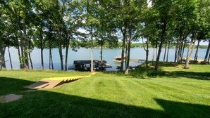 A grassy area with a dock and a boat, surrounded by trees and a body of water. - What A View, Wifi, ping pong, cloe to amenities (Moneta)