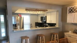 A modern kitchen with a central island, bar stools, and a dining area with a glass table. - What A View, Wifi, ping pong, cloe to amenities (Moneta)