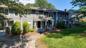 A two-story residential building with a front porch, a small garden, and a well-maintained lawn. - What A View, Wifi, ping pong, cloe to amenities (Moneta)