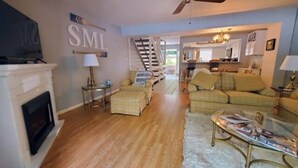 A spacious living room with a fireplace, a sofa set, a glass coffee table, and a staircase leading to an upper level. - What A View, Wifi, ping pong, cloe to amenities (Moneta)