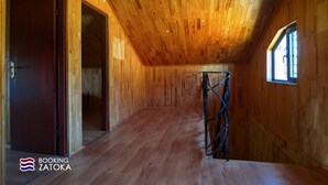 Un intérieur en bois avec un plafond en pente, une fenêtre et une porte.