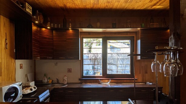 Une cuisine avec des meubles en bois, un lave-linge encastré, une grande fenêtre donnant sur l’extérieur et un meuble à vin.