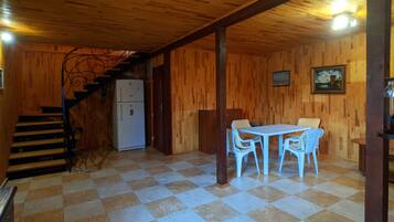 Un interior de madera con piso a cuadros, una mesa de comedor con sillas, un refrigerador y una escalera.