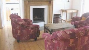 Ein Wohnzimmer mit gemusterten Sofas, einem Kamin und einem Holzboden.