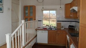 Eine kleine Küche mit Holzschränken, einem Fenster und einem weißen Geschirrspüler.