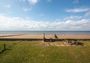 Relax on the beach with a clear ocean view, a bench, and a picnic table.